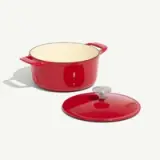 A red enameled cast iron pot with its lid placed beside it.