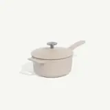 A cream-colored saucepan with a lid and a handle is set against a plain background.