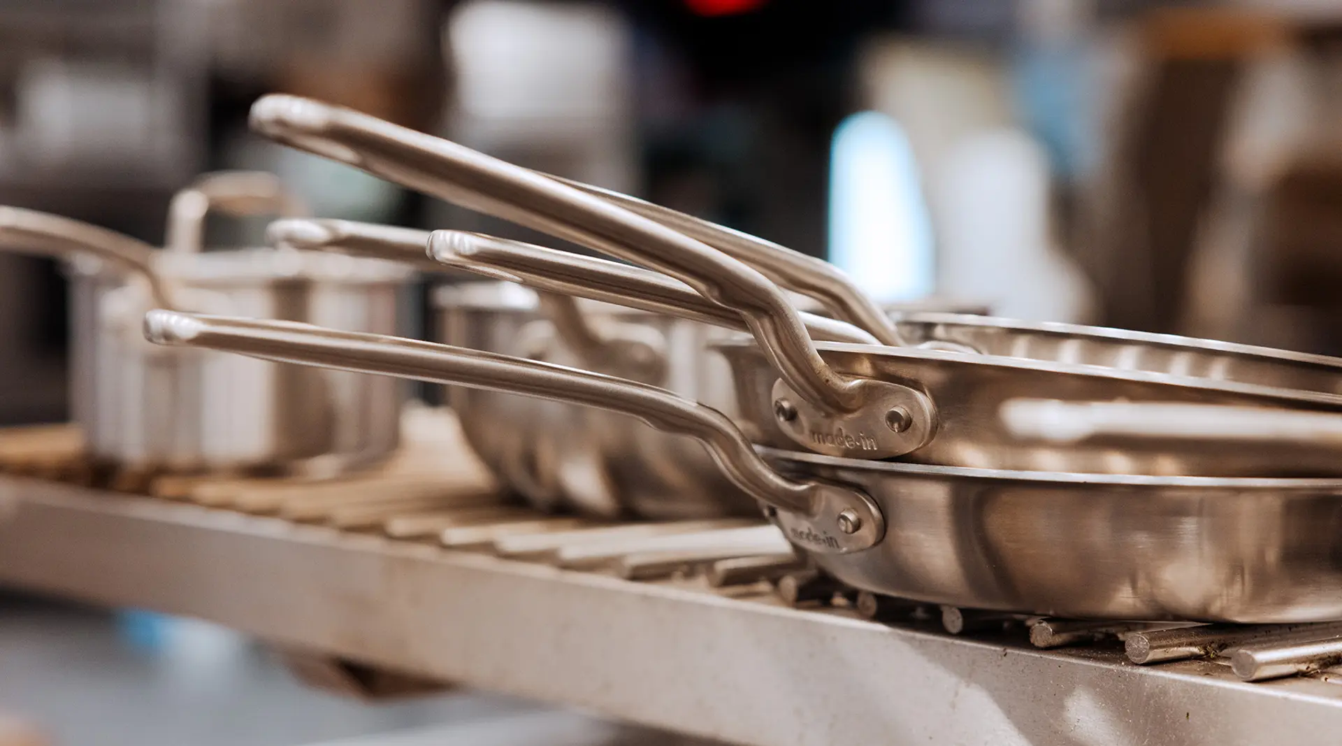 A set of stainless steel pots and pans are neatly stacked on a kitchen rack.