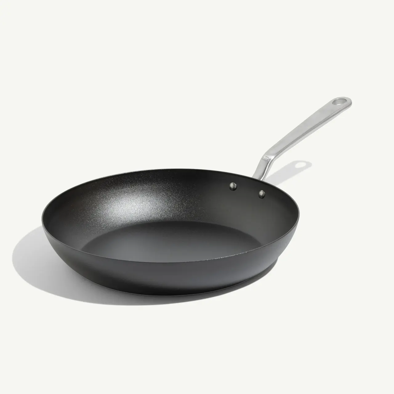 A black non-stick frying pan with a stainless steel handle is displayed against a light background.