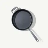 A non-stick frying pan with a long handle and an additional helper handle on a light background.