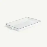 A rectangular white ceramic baking dish with handles on both ends and a thin dark rim is shown against a light background.