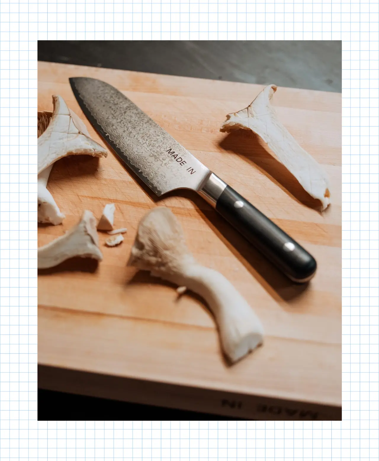 A kitchen knife is placed on a wooden cutting board along with several pieces of cut mushroom.