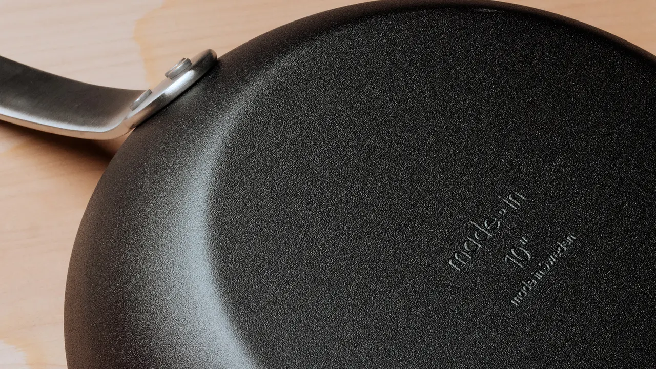 Close-up view of a non-stick frying pan with its handle partially visible and the brand name 'made in' embossed at the center.