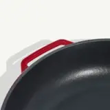 A close-up view shows a black cooking pan with a red handle.
