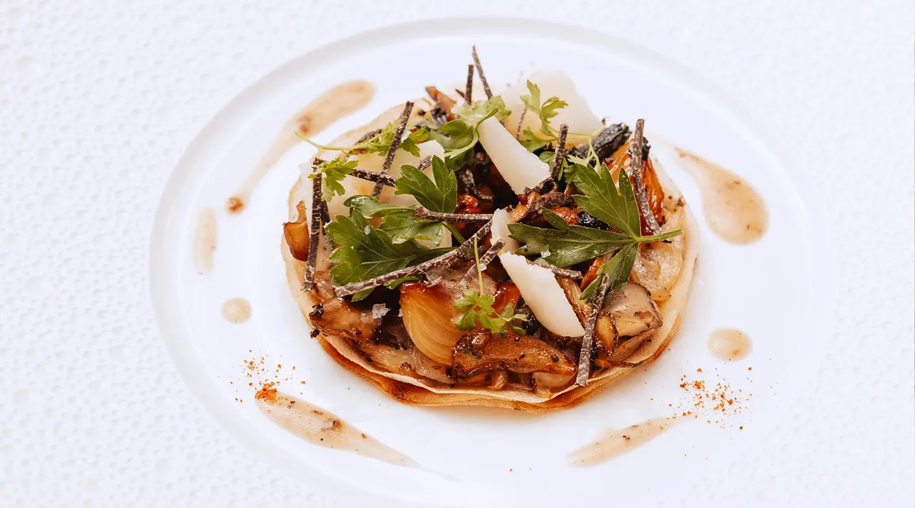 A beautifully plated dish featuring sautéed vegetables, garnished with fresh herbs and drizzled with sauce, served on a circular white plate.