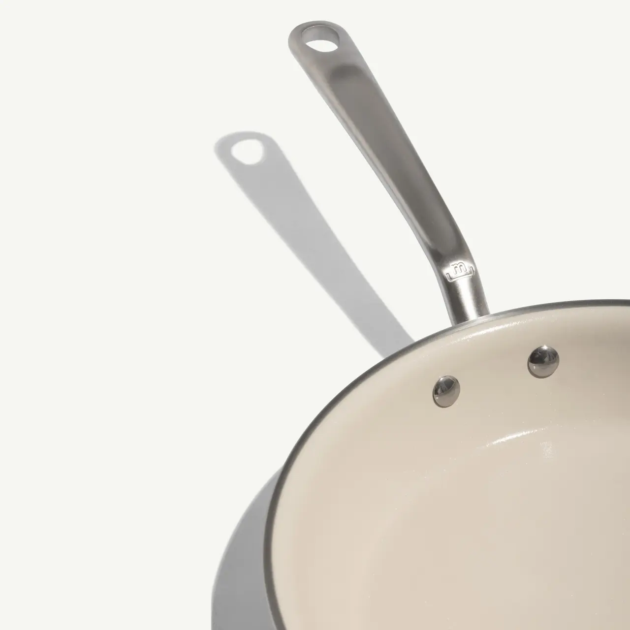 A clean, stainless steel frying pan with a light interior, showcasing a sleek design and a sturdy handle.