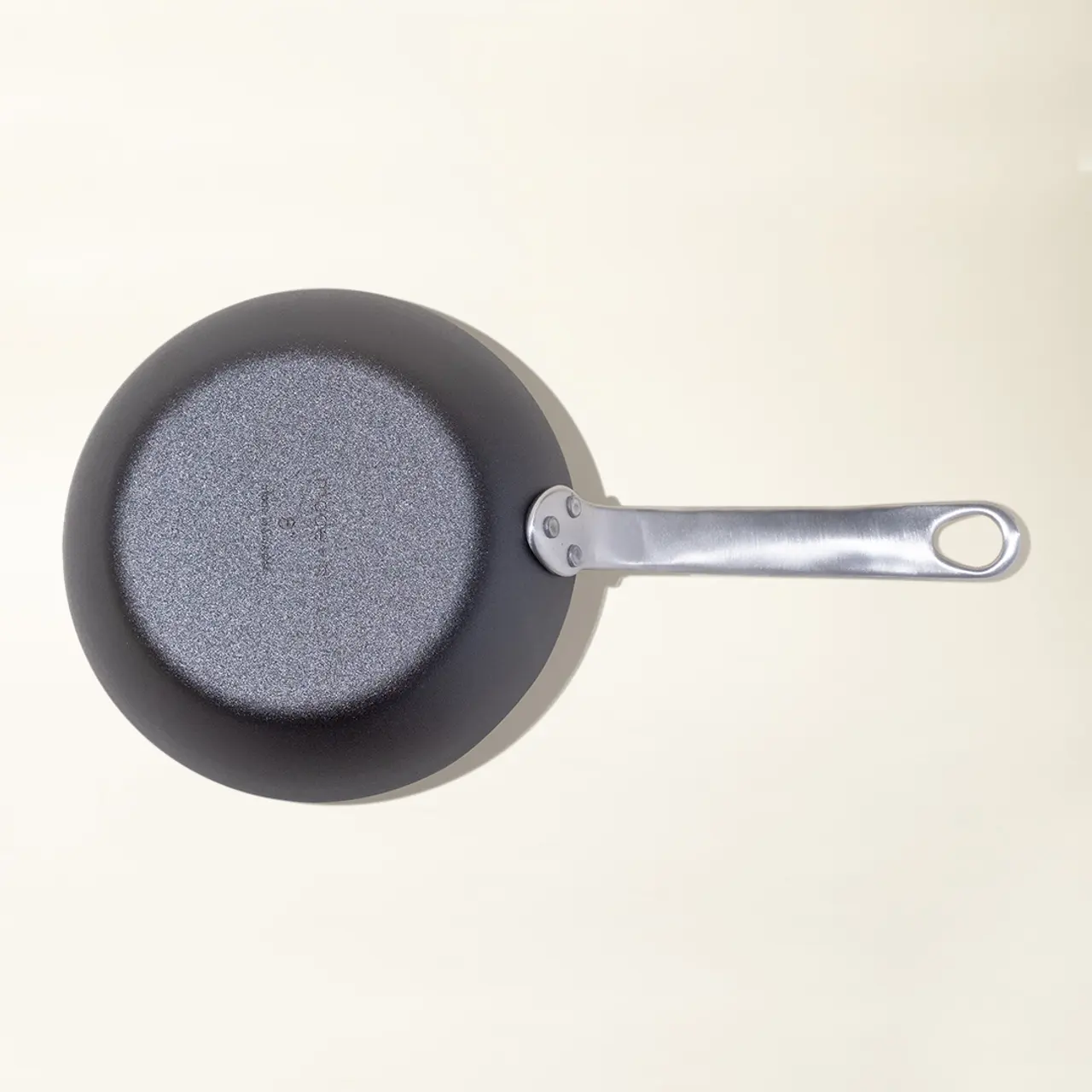 A non-stick frying pan with a silver handle is shown from above on a light background.