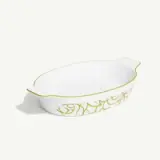 White oval ceramic baking dish with green decorative patterns and handles on a plain background.