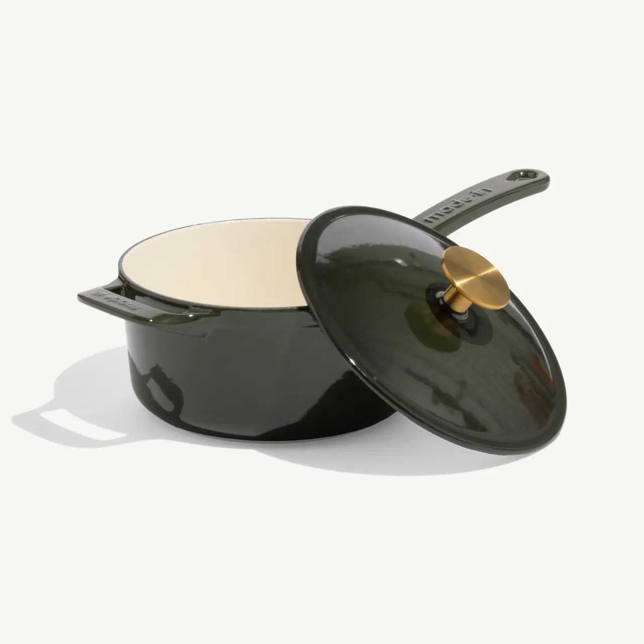 A dark green enameled cast iron pot with a matching lid, featuring a brass knob, sits on a neutral background.