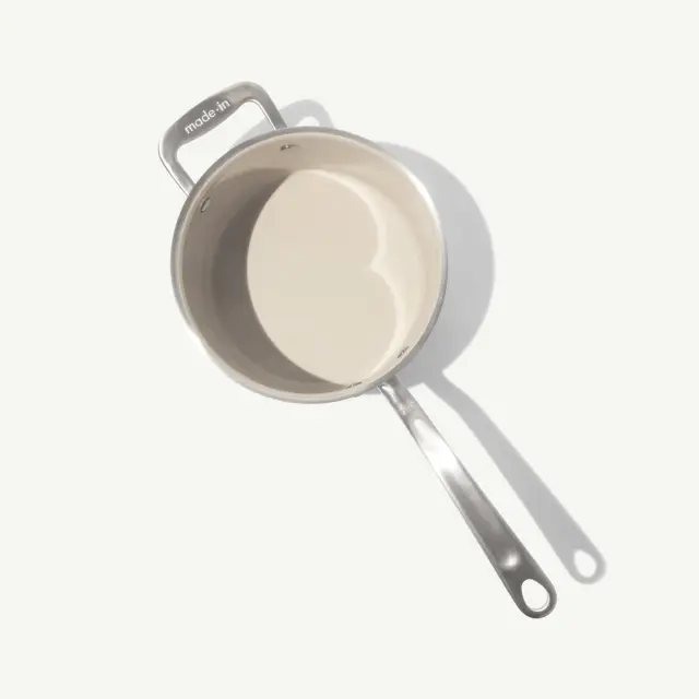 A stainless steel saucepan with a long handle is shown from a top-down perspective, featuring a smooth, reflective interior.