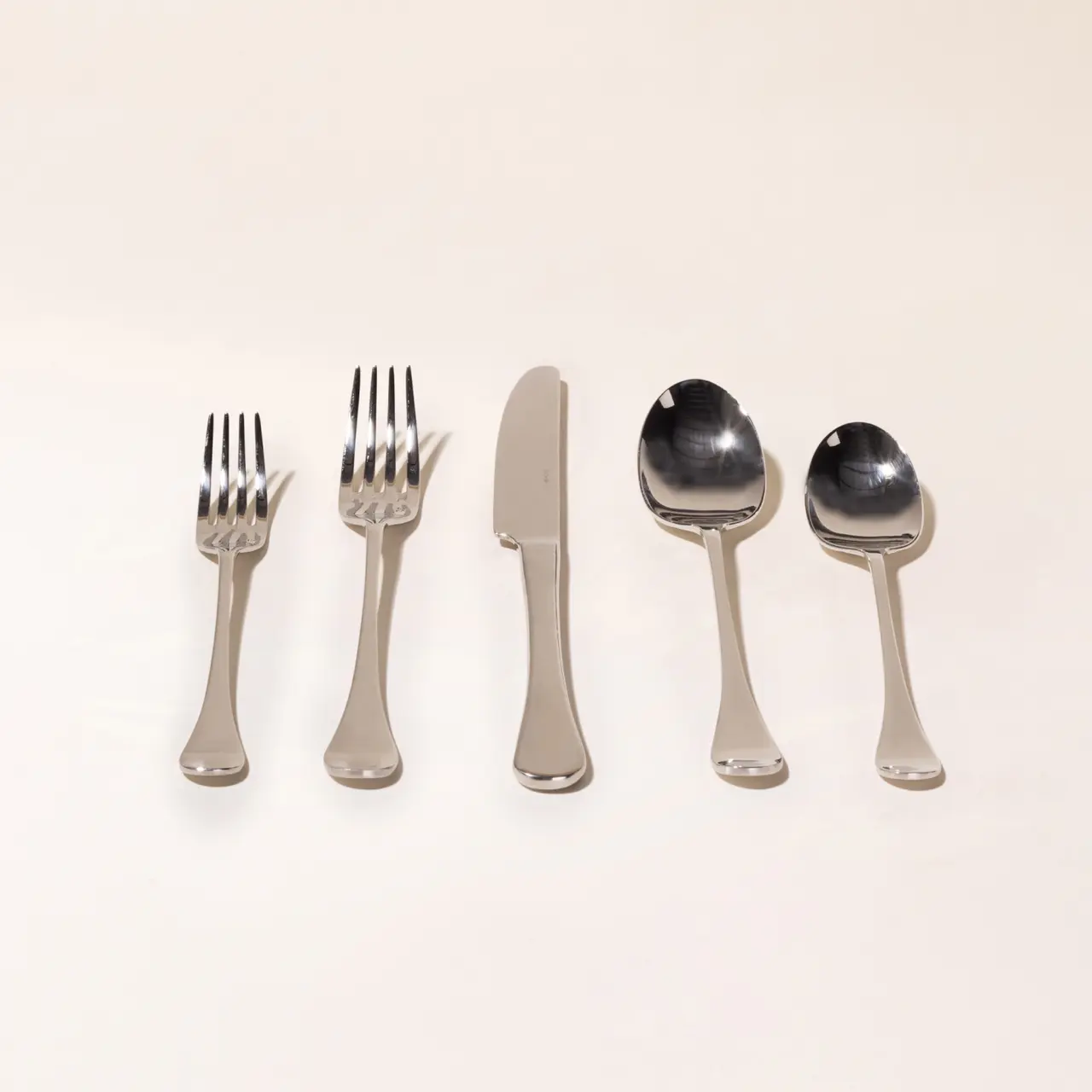 Five pieces of silverware, consisting of forks, a knife, and spoons, are neatly arranged on a light background.