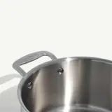 A stainless steel pot with a visible handle against a plain background.