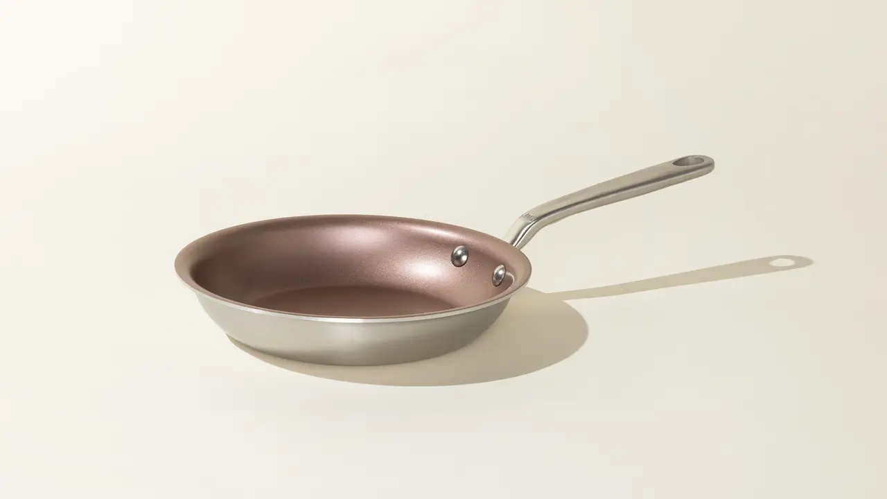 A non-stick frying pan with a stainless steel handle is set against a neutral background.