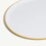A white oval plate with a thin yellow rim.