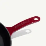 A red cast iron frying pan with a smooth, black interior and a handle featuring the inscription "made-in."