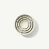 Four nested white bowls of varying sizes are arranged concentrically against a plain background.