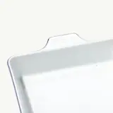 A rectangular white baking dish with blue edges and the words "made in" embossed on one handle.