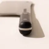 A close-up of a metallic ballpoint pen lying diagonally on a white surface, casting a soft shadow.