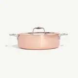 A shiny copper pot with a lid and side handles is centered on a plain white background.