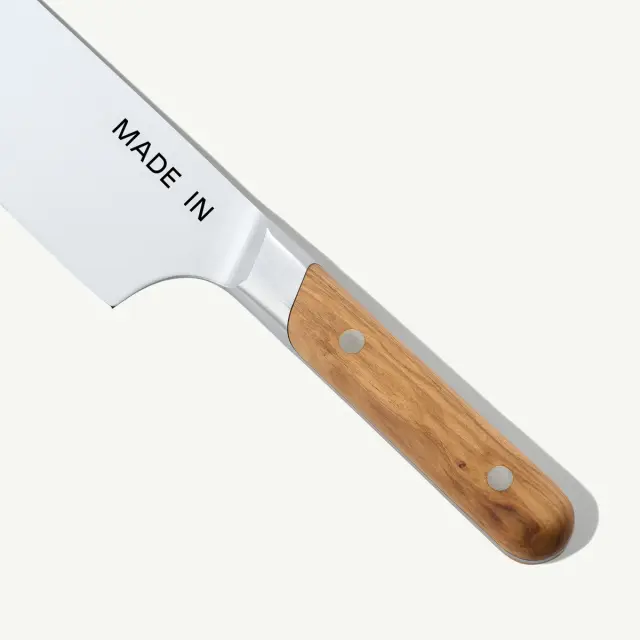 A stainless steel kitchen knife with a wooden handle and the words "MADE IN" engraved on the blade.