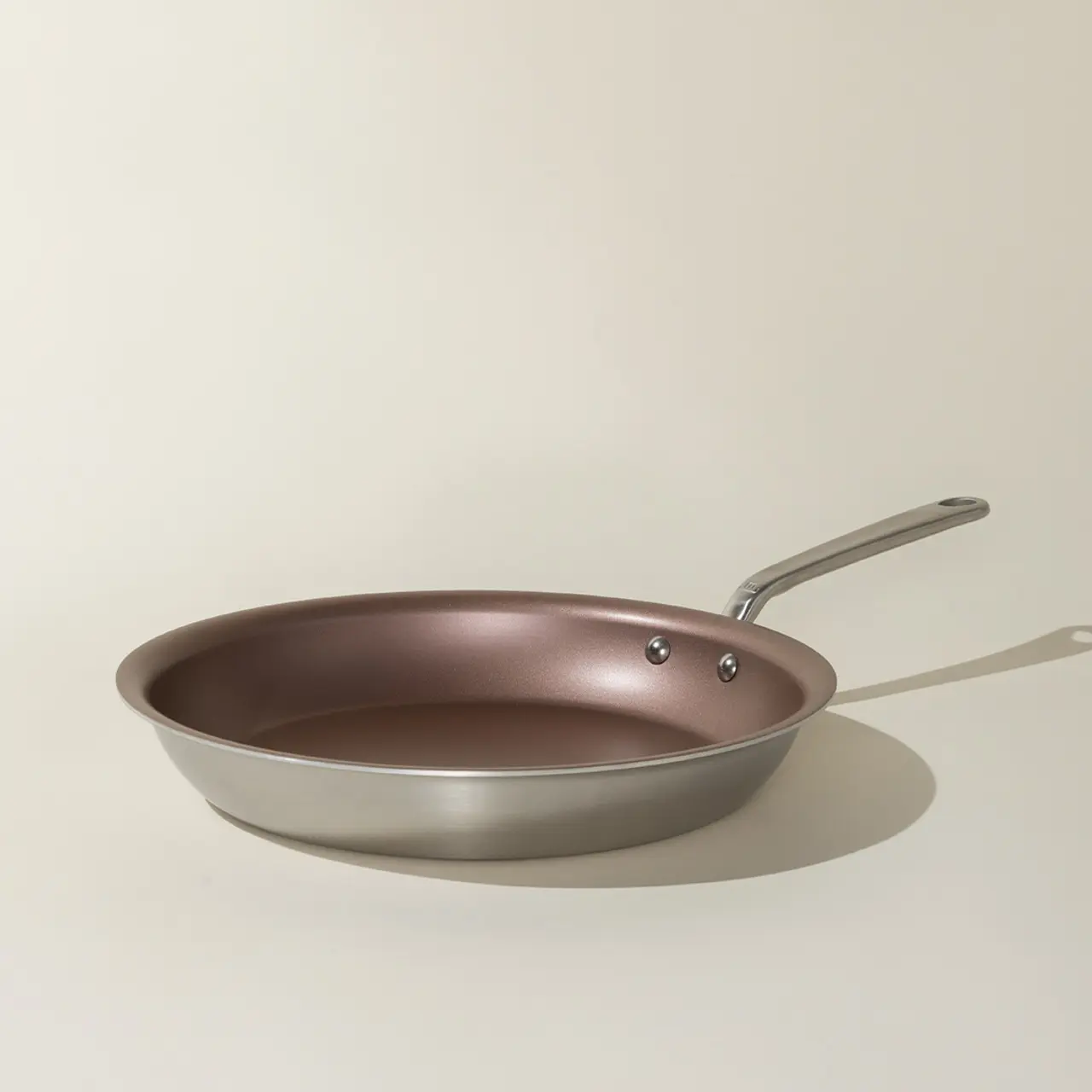 A non-stick frying pan with a stainless steel handle sits on a neutral background.
