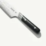 A chef's knife with a black handle and a blade inscribed with "MADE IN."