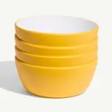 A stack of four yellow bowls with white interiors on a white background.