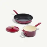 A red cookware set featuring a frying pan and a small pot with a lid, showcasing a sleek design and contrasting interior colors.