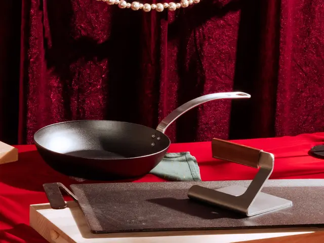 A frying pan hovers above a knife sharpener on a table with a red cloth backdrop, suggesting the surreal suspension of the pan in mid-air.