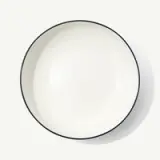 A white ceramic bowl with a black rim is pictured against a plain background.
