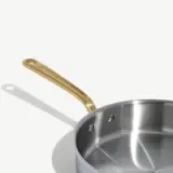 A stainless steel saucepan with a sleek, metallic finish and a gold-tone handle.