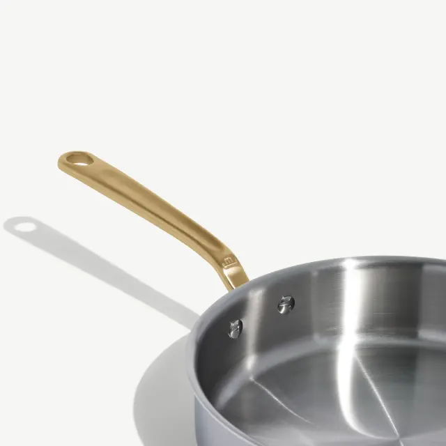 A stainless steel saucepan with a sleek, metallic finish and a gold-tone handle.