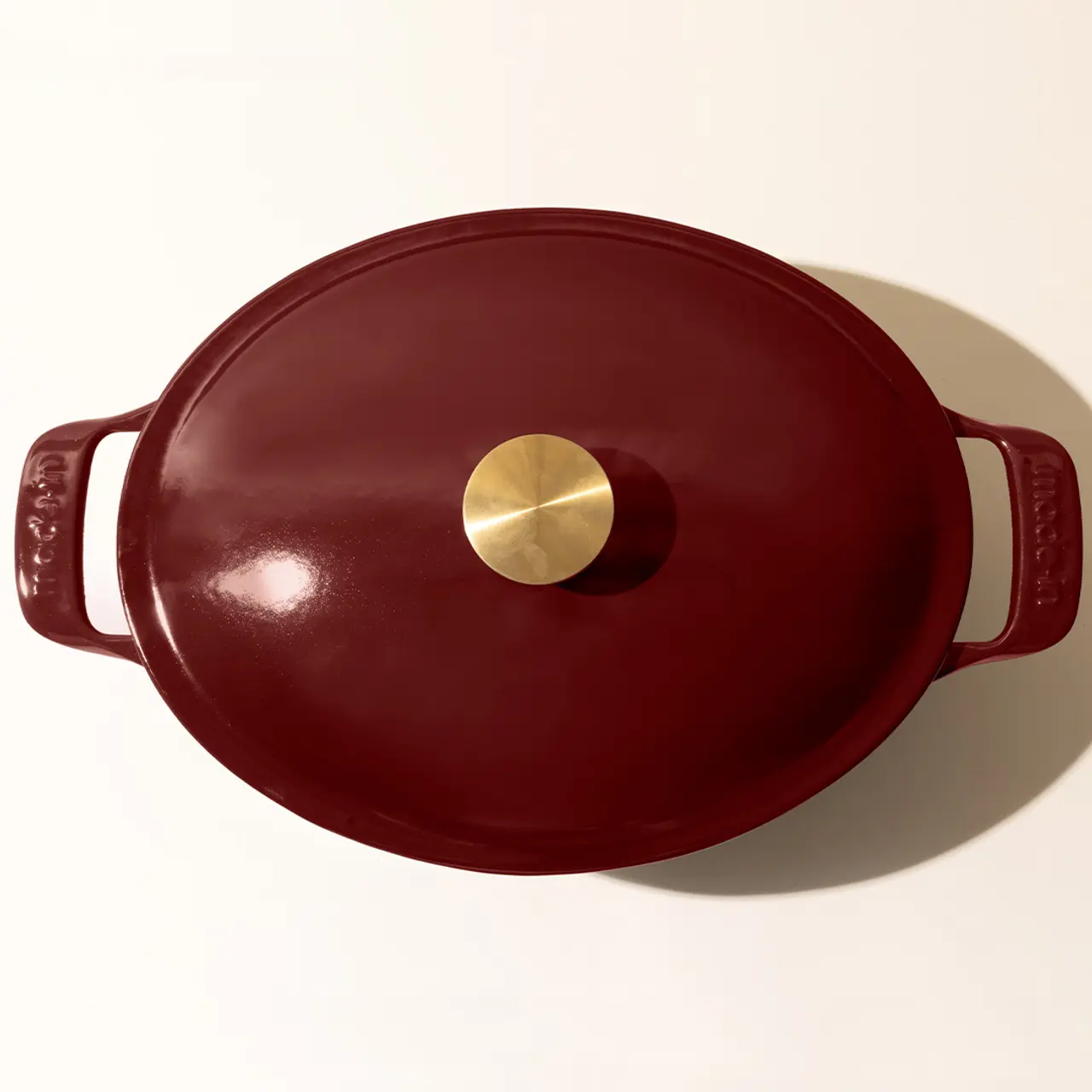 A red enameled cast iron Dutch oven with a lid featuring a golden knob, viewed from above.