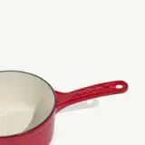 Red saucepan with a long handle and white interior.
