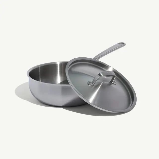 A stainless steel saucepan with a matching lid is placed on a flat surface.