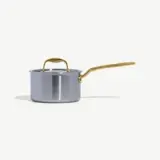 A sleek, silver pot with a gold handle rests on a neutral background.