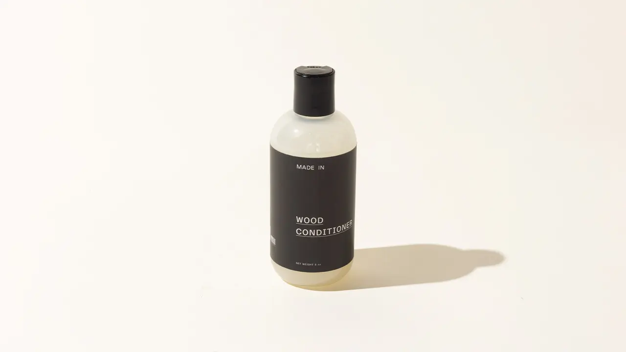A bottle labeled "WOOD CONDITIONER" stands on a plain background, casting a soft shadow.