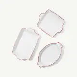 Three white ceramic baking dishes with red edges are arranged on a white background.