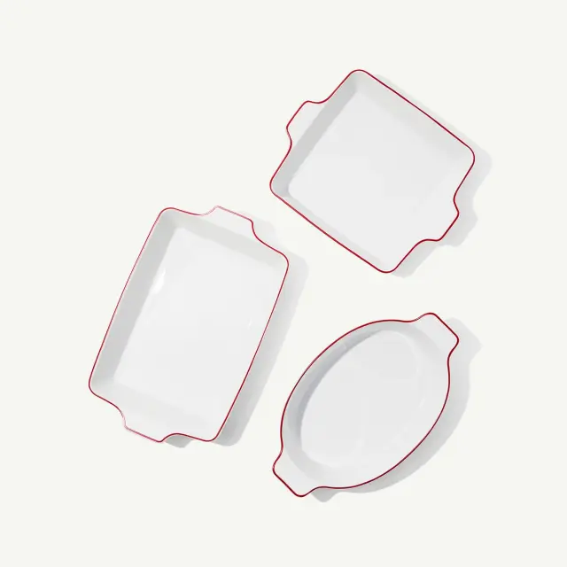 Three white ceramic baking dishes with red edges are arranged on a white background.