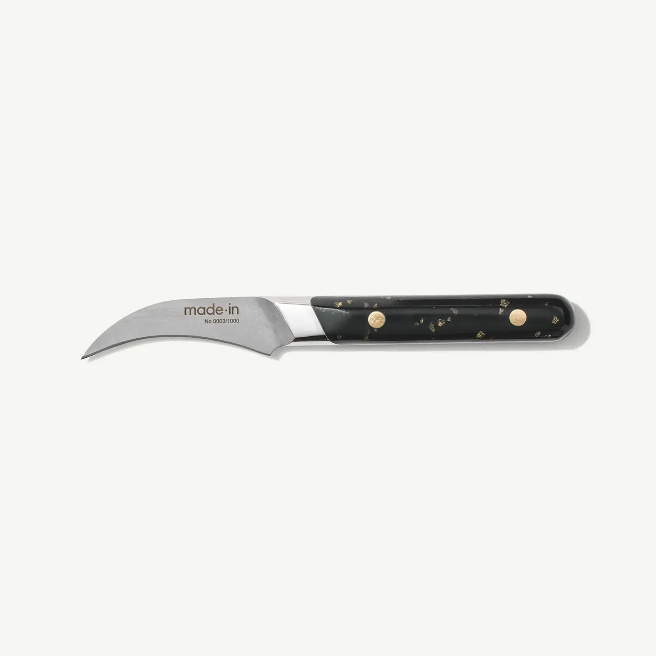 A curved paring knife with a black handle and the brand name "made in" printed on the blade.