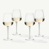 Four elegant wine glasses filled with white wine, casting soft shadows on a light background.