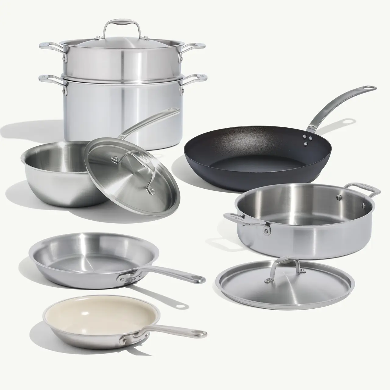 A collection of various cookware, including stainless steel pots, pans, and a steamer set, arranged on a light background.