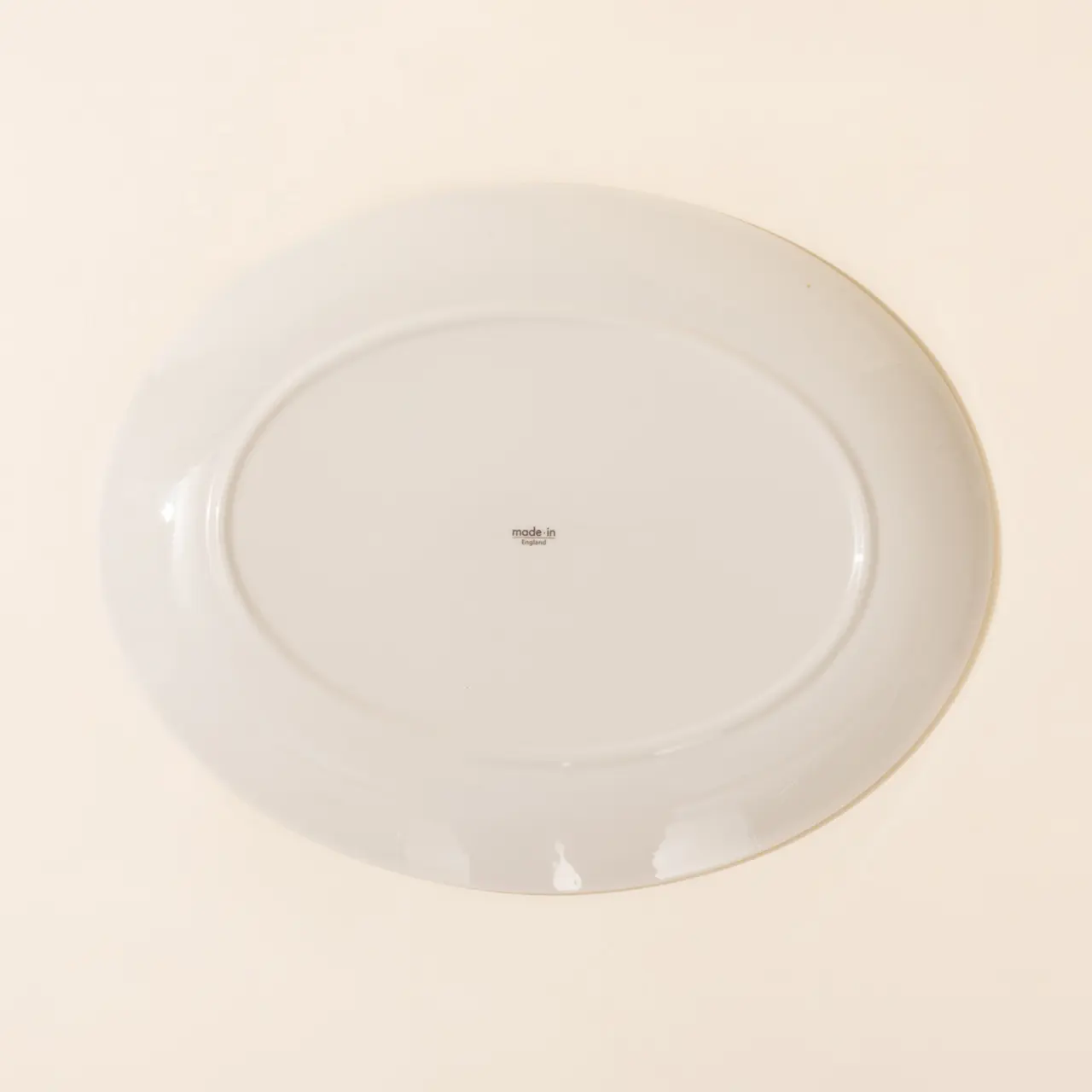 A plain white oval plate is centered on a light backdrop.
