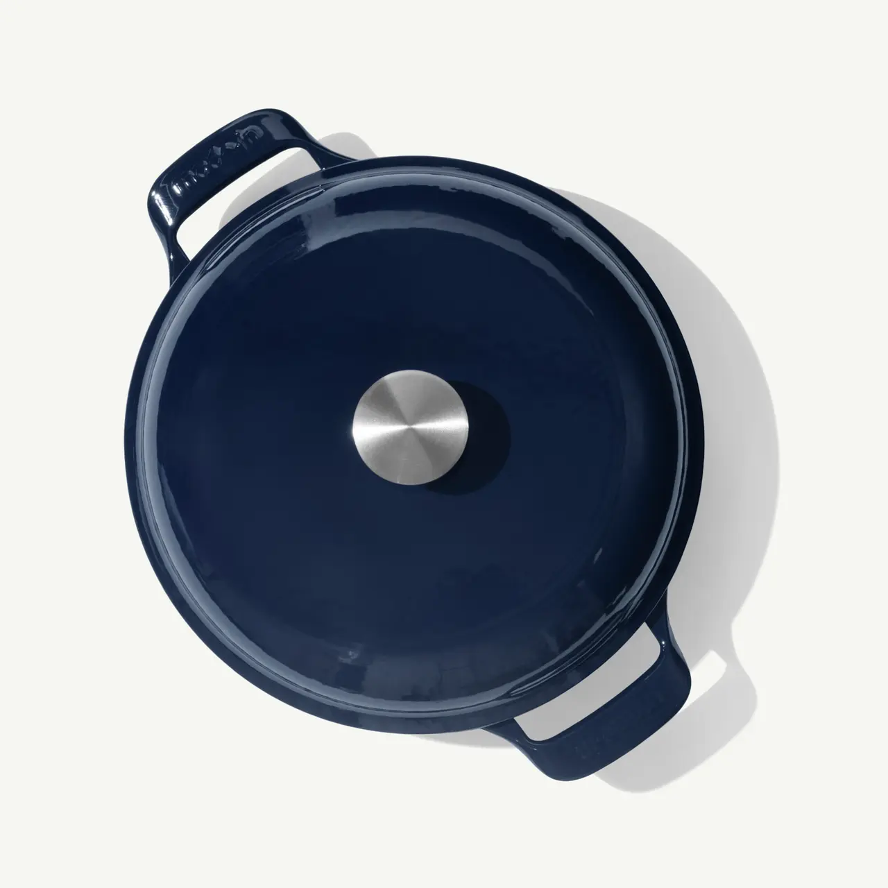 A deep blue cast iron pot with a stainless steel handle on the lid is shown from above.