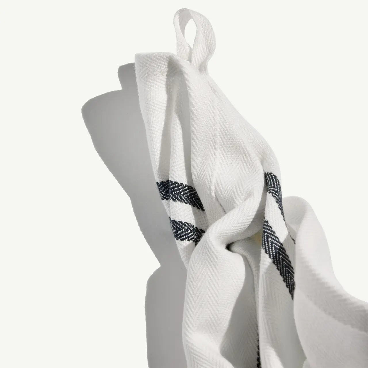 A white towel with a black and white herringbone pattern edge is draped elegantly with a soft fold.