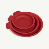 A set of three nested red silicone baking pans lies on a white background.