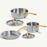 Set of stainless steel cookware featuring a large saucepan, a small saucepan with a lid, and a frying pan, all with gold handles.