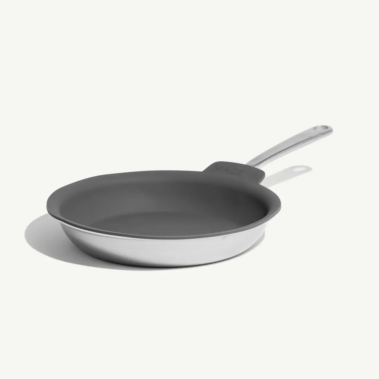 A non-stick frying pan with a grey interior and silver handle is placed on a plain white background.