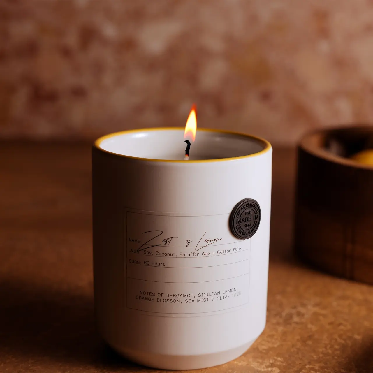 A lit scented candle with a visible label stands on a table, providing a warm ambiance.